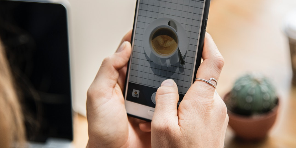 woman taking picture of coffee on phone