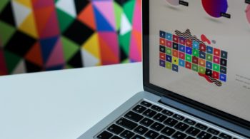 laptop against abstract wall with logo design on screen