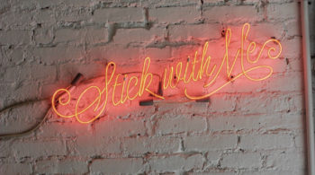neon sign on wall that says stick with me